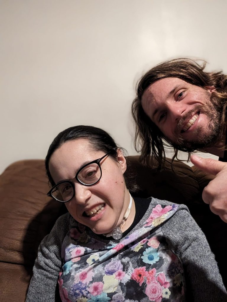 Esther smiling with Corbin behind her giving a thumbs up.